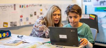 Teacher and child using laptop